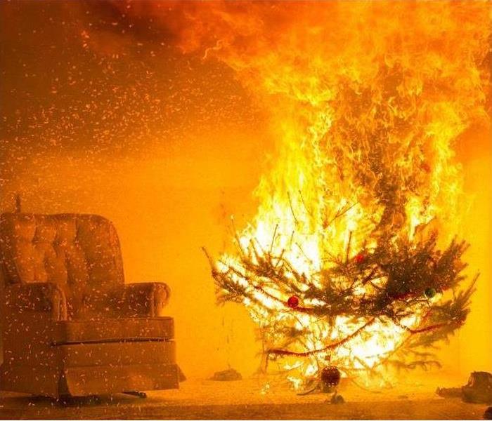 A Christmas tree positioned in front of curtains engulfed in orange and yellow fire flames.