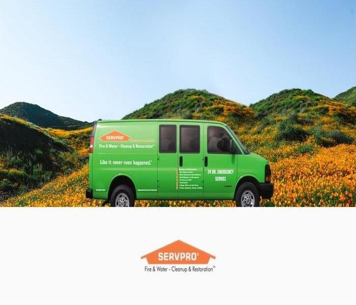Green SERVPRO van in front of a hill of orange poppies, blue skies