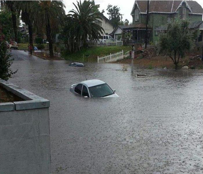 homes with street flooded with rain water and a car in the flood water