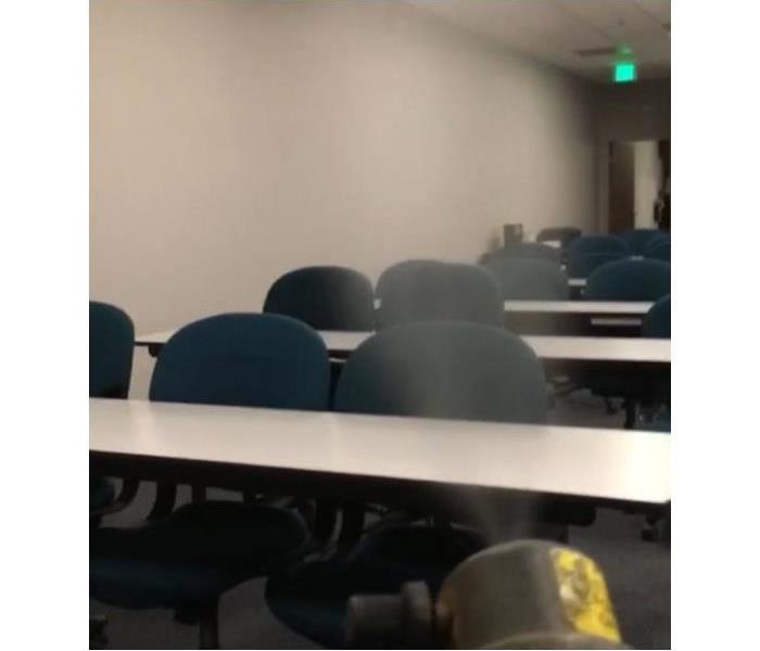 fogger spraying into room with chairs and brown desks