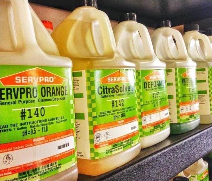 5 jugs of various cleaning products with SERVPRO labels sitting on a metal shelf.