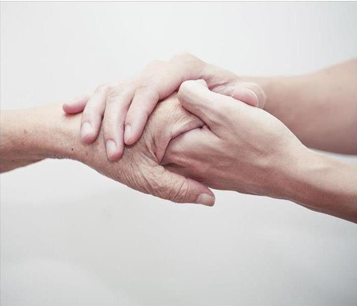 a young hand holding the hand of an elderly person